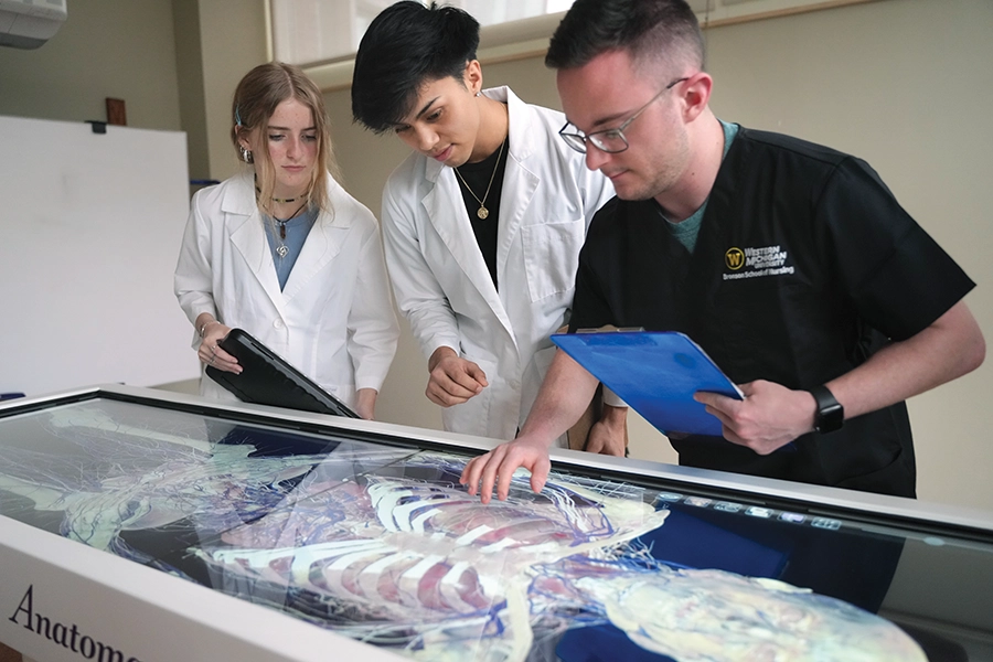 3 med students researching and observing virtual resources in a lab.