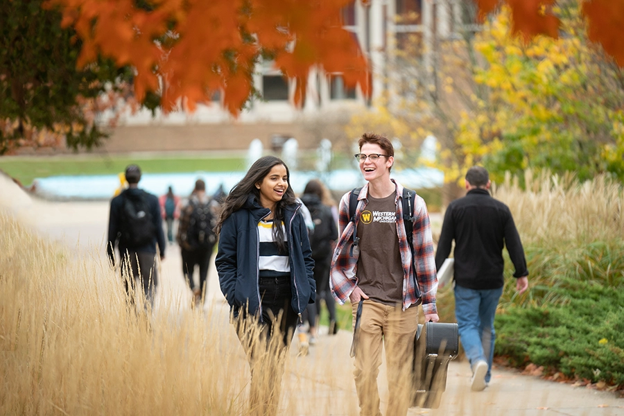2 students walking outside to class having a conversation.